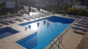 Alberca al aire libre, sombrillas en la alberca y camastros