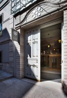 Entrada de un edificio con una puerta grande y decorativa, e indicación de que se encuentra en el primer piso.