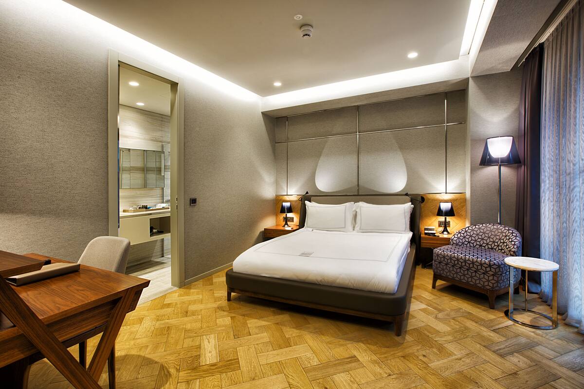 Une chambre d’hôtel moderne avec un grand lit, un bureau, une chaise et une petite table.