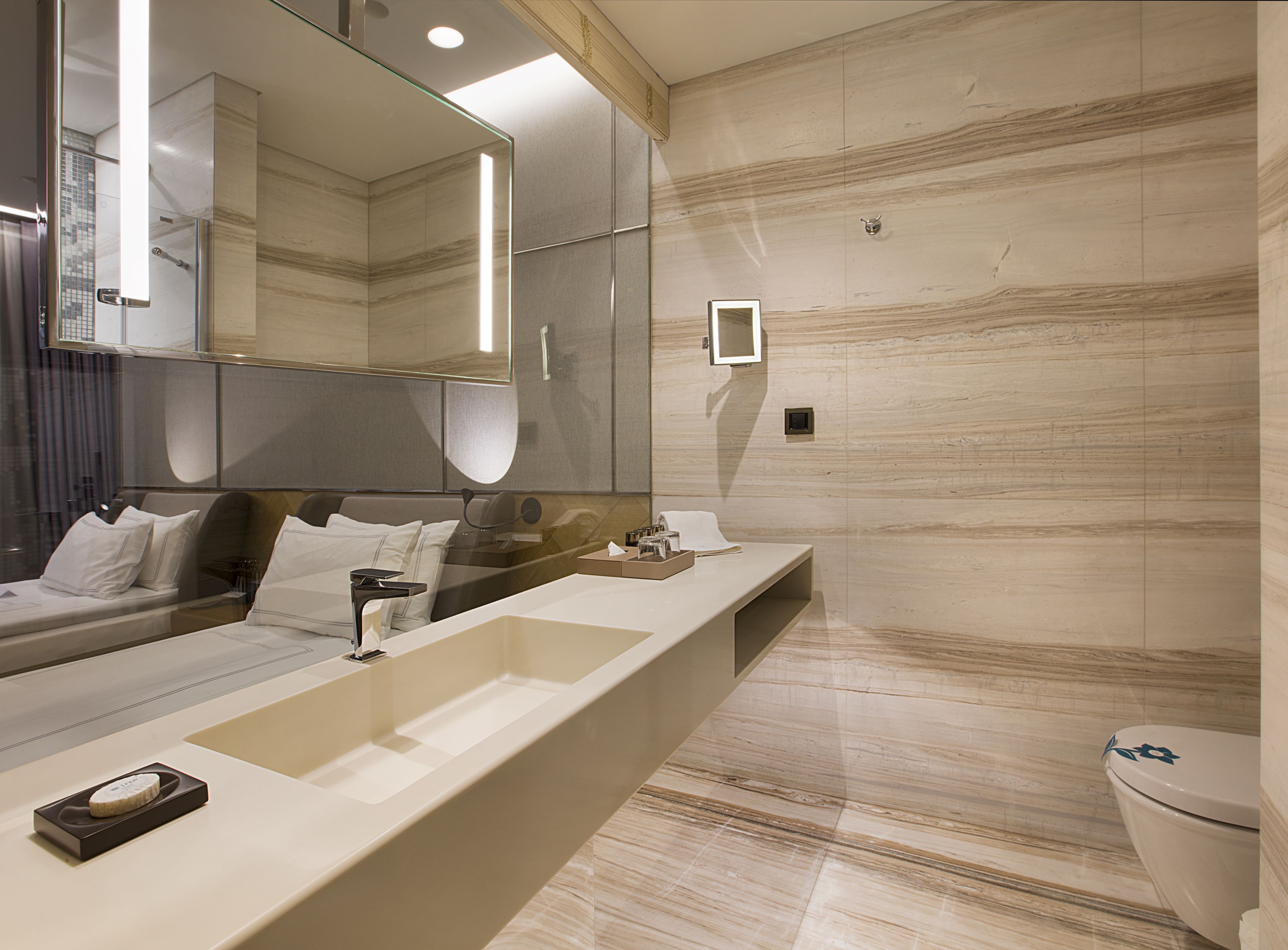 Un baño moderno con un espejo grande, una bañera y un inodoro.