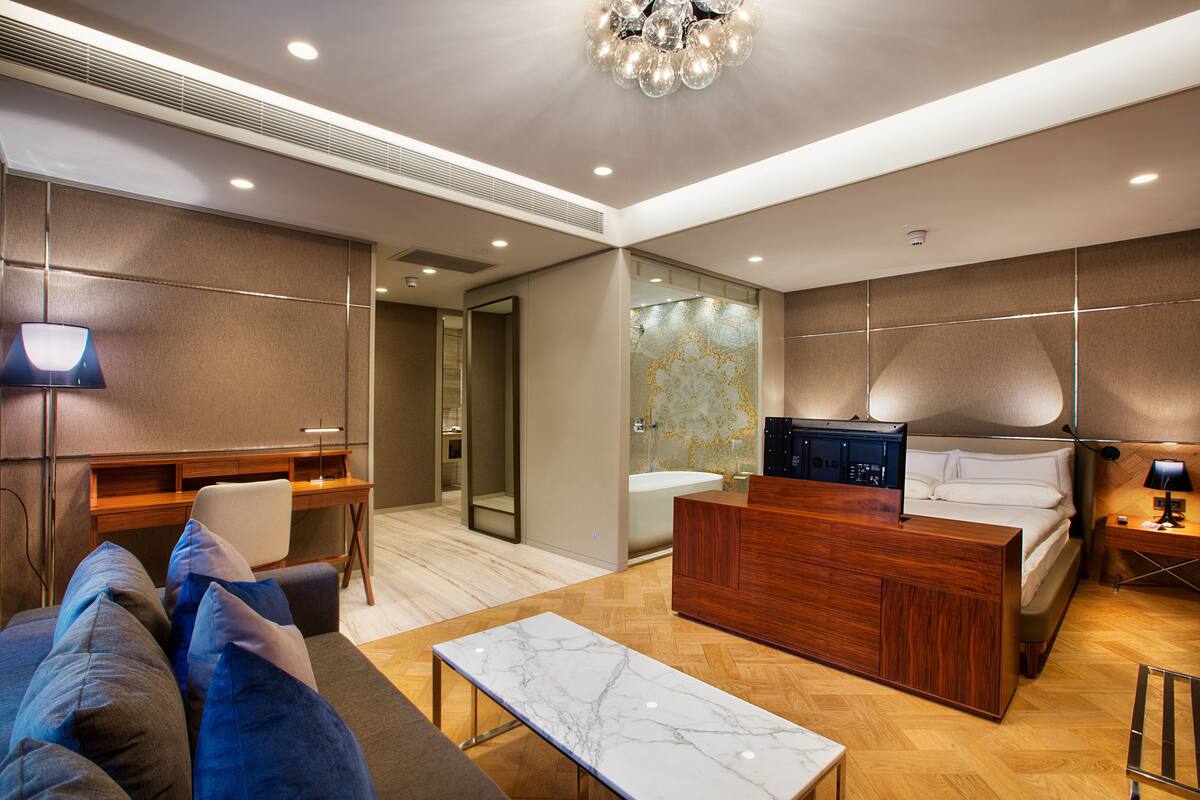 Une chambre d’hôtel moderne, dotée d’un bureau en bois, d’un grand lit, d’un canapé et d’une salle de bain avec baignoire.