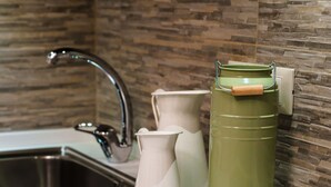A kitchen with a modern sink, a green water container, and two white pitchers on the counter. - Guest House Grazioli (Rome)