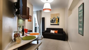 A compact living space with a kitchen area, dining table, and a sofa. - Guest House Grazioli (Rome)