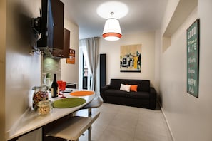 A compact living space with a kitchen area, dining table, and a sofa. - Guest House Grazioli (Rome)