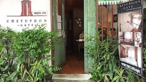 The entrance to Chetuphon Gate with a signboard, potted plants, and a poster advertising room rates. - Chetuphon Gate (Bangkok)
