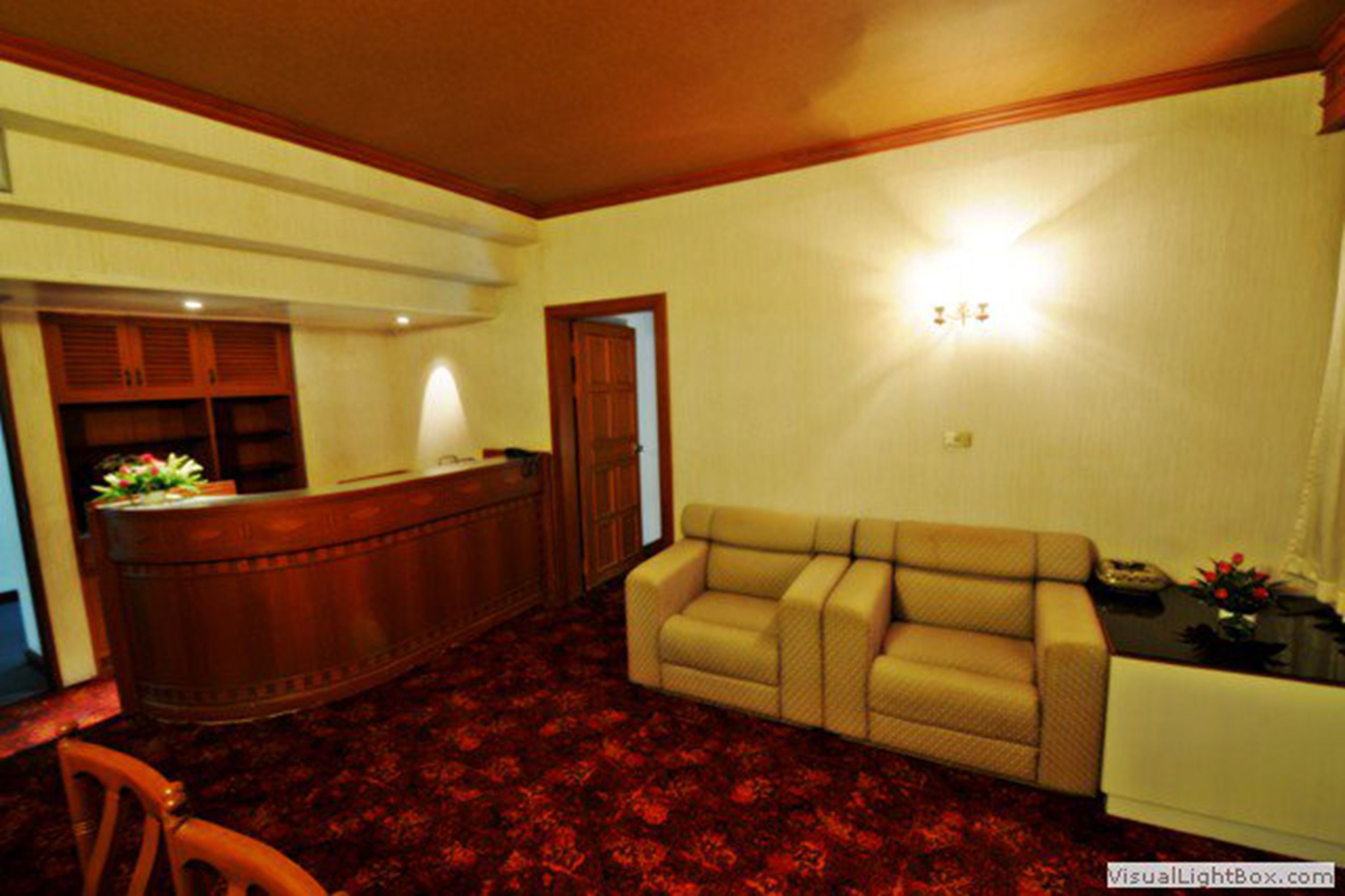 A living room with a sofa, a wooden reception desk, and a red carpet.