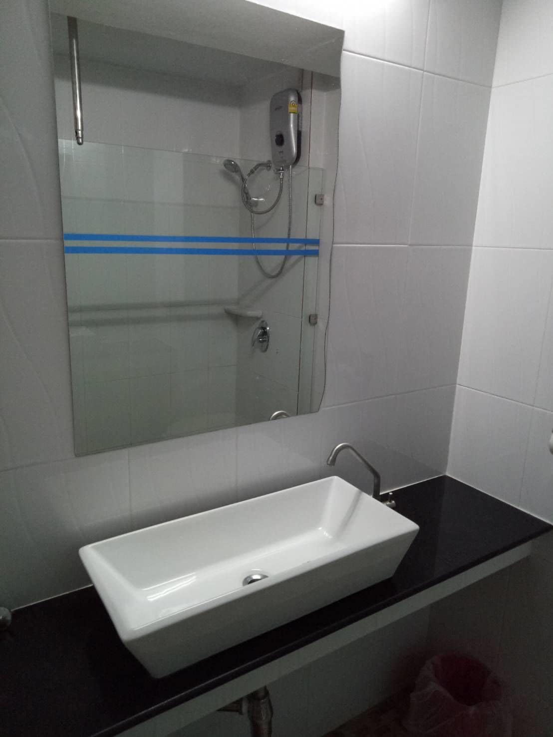 A bathroom with a white sink, a mirror, and a shower with a handheld showerhead.