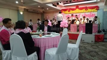 A conference room with round tables, chairs, and a stage with a band performing.