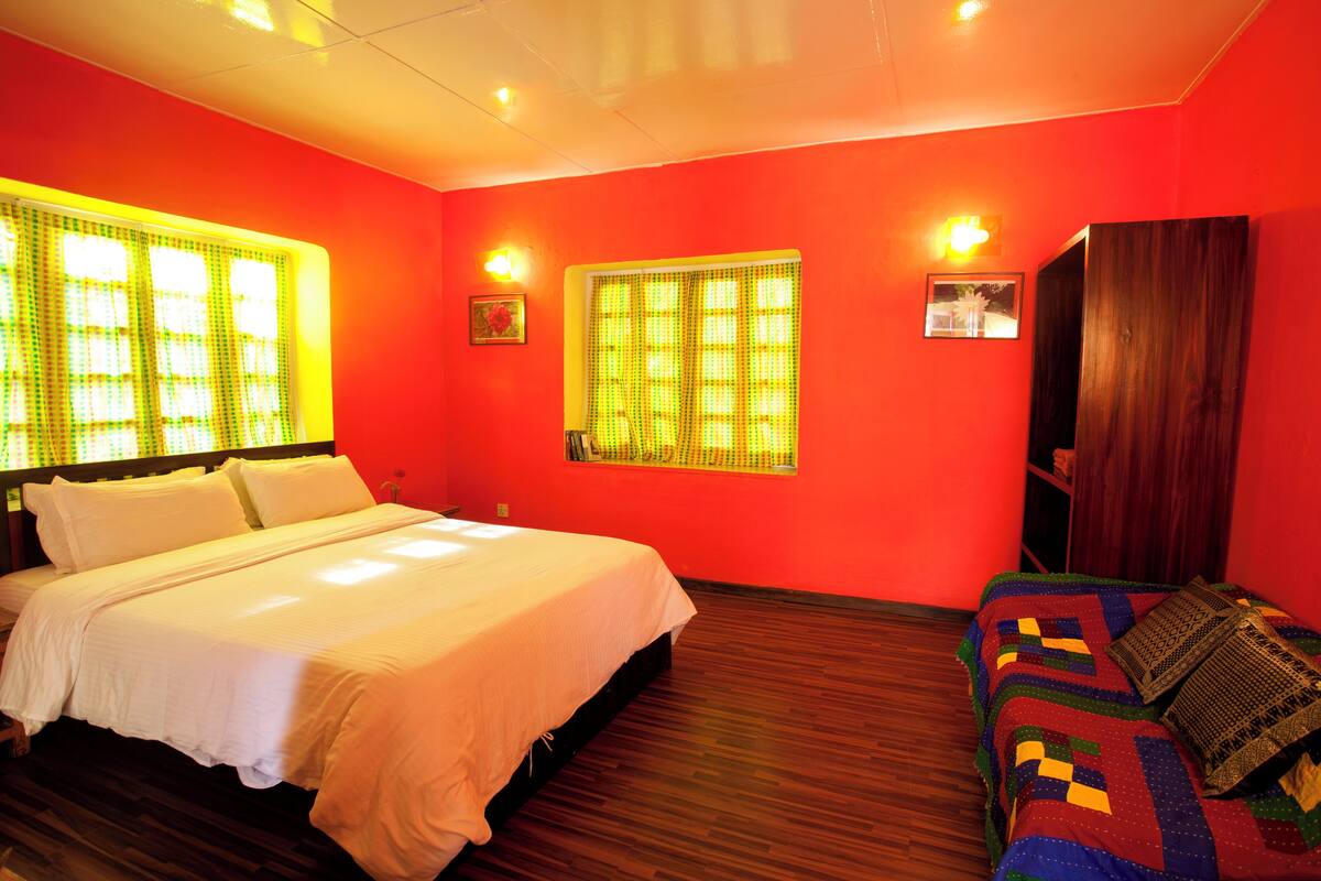 A room with a bed, a sofa, and two windows with curtains.
