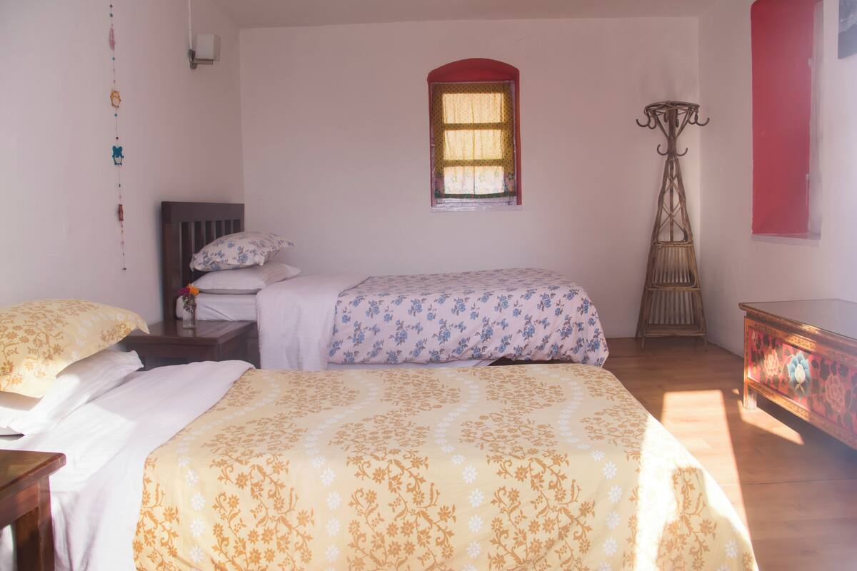 A bedroom with two beds, a window, a floor lamp, and a dresser.