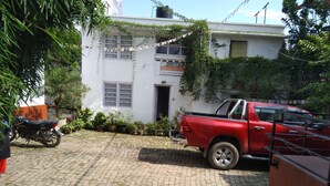 A red pickup truck parked in a driveway with a white building in the background. - Cocina Mitho Chha (Kathmandu)