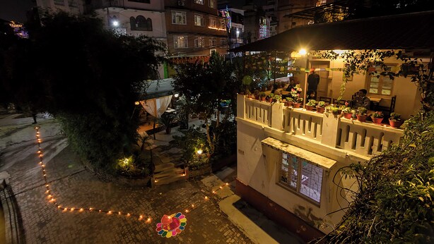 A building with multiple balconies, potted plants, and a paved courtyard. - Cocina Mitho Chha (Kathmandu)