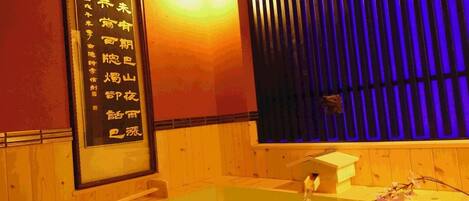 A traditional Japanese onsen with a wooden interior, a glass-enclosed hot spring bath, and a wall-mounted sign with Chinese characters.