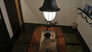 Et træbord med en elkedel og en lampe, omgivet af grønne puder.