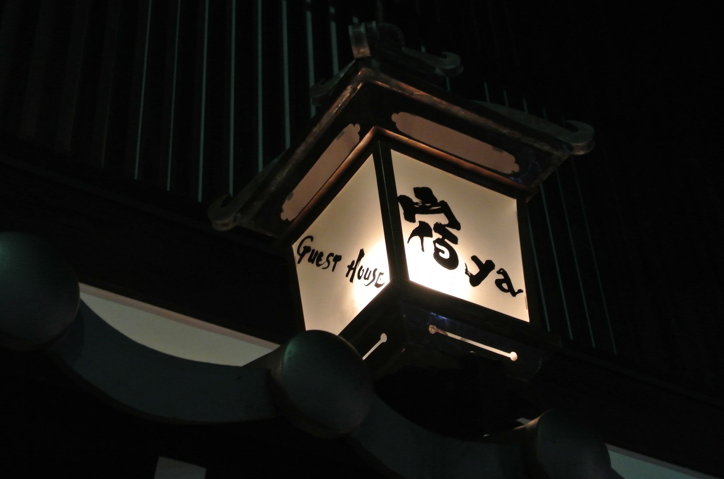 Lanterna com caracteres japoneses e a inscrição "Guest House".