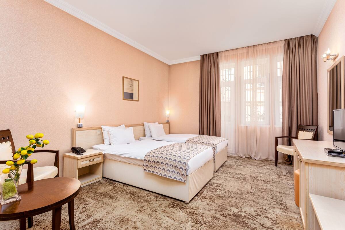 A hotel room with a large bed, bedside tables, a desk, and a chair.