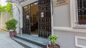 Entrada de un hotel con una verja de hierro forjado, un letrero que dice 'HOTEL SHARDEN' y escalones que conducen a la puerta.