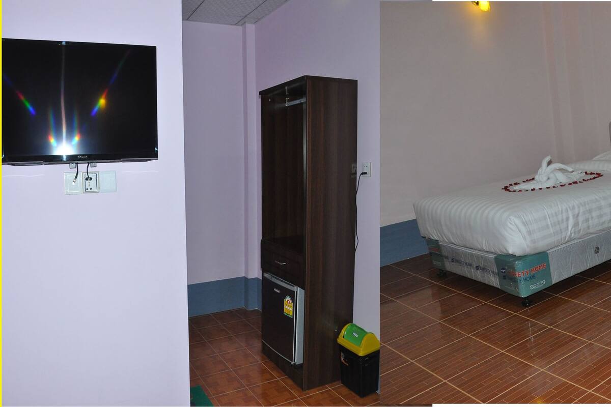 A hotel room with two beds, a television, a wardrobe, and a small trash bin.