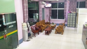 Una habitació d'hotel amb zona de menjador, un finestral gran amb cortines, televisió i nevera.