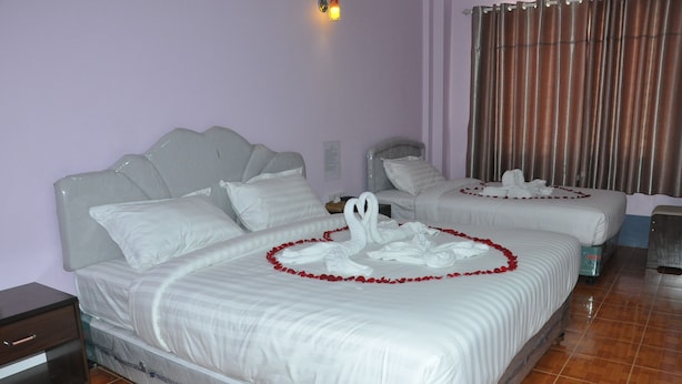 Una habitació d'hotel amb dos llits, cadascun decorat amb roba blanca i guirlands de flors vermelles.