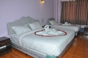 Una habitación de hotel con dos camas, cada una decorada con sábanas blancas y guirnaldas de flores rojas.