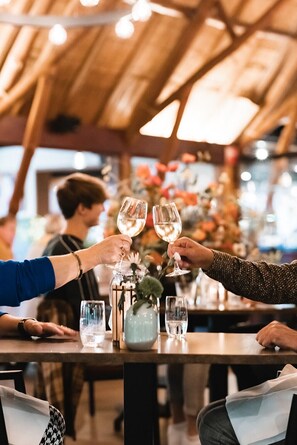 Un grupo de personas brindando con copas de vino en una mesa de madera en un restaurante.