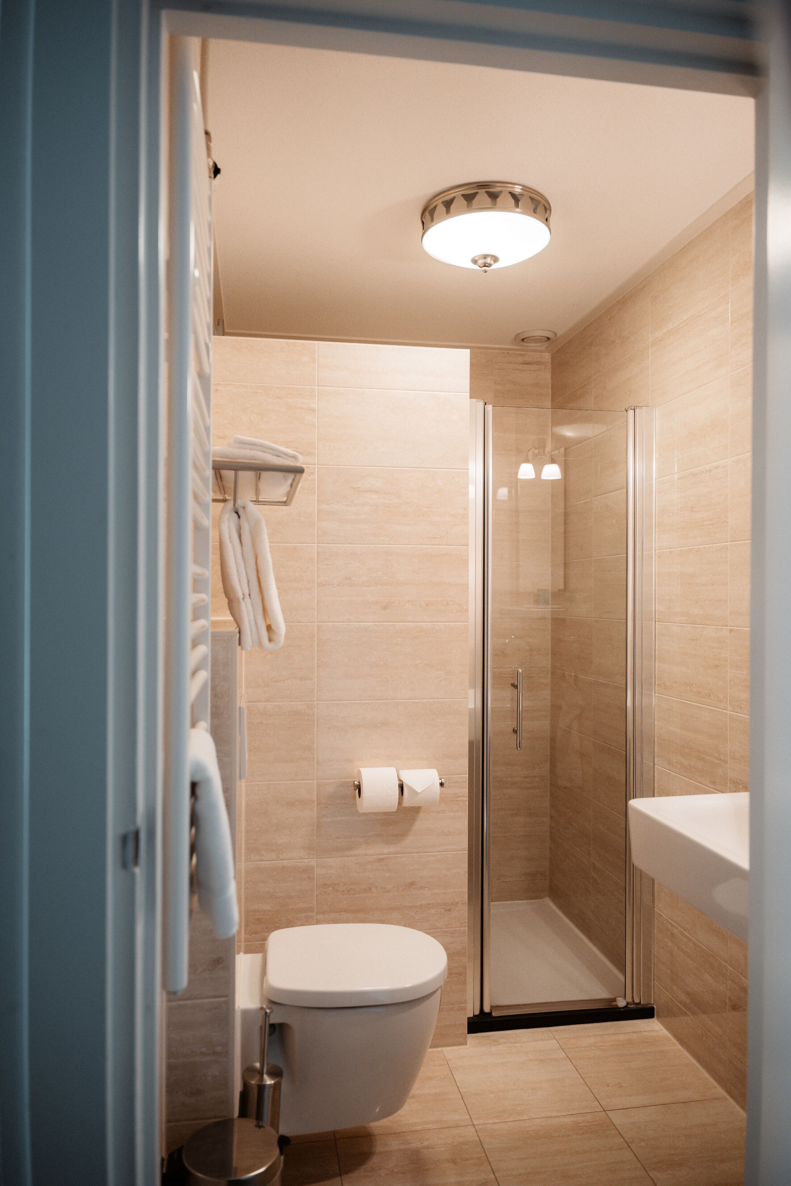 A modern bathroom with a glass-enclosed shower, a toilet, and a sink.