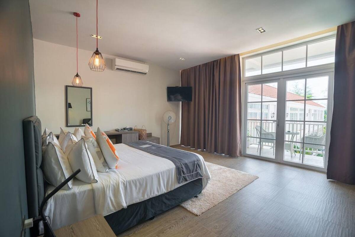 Una habitación de hotel moderna con una cama grande, un televisor de pantalla plana, un escritorio y vistas al exterior.
