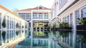 Un hotel con piscina, reflejando edificios y el cielo.