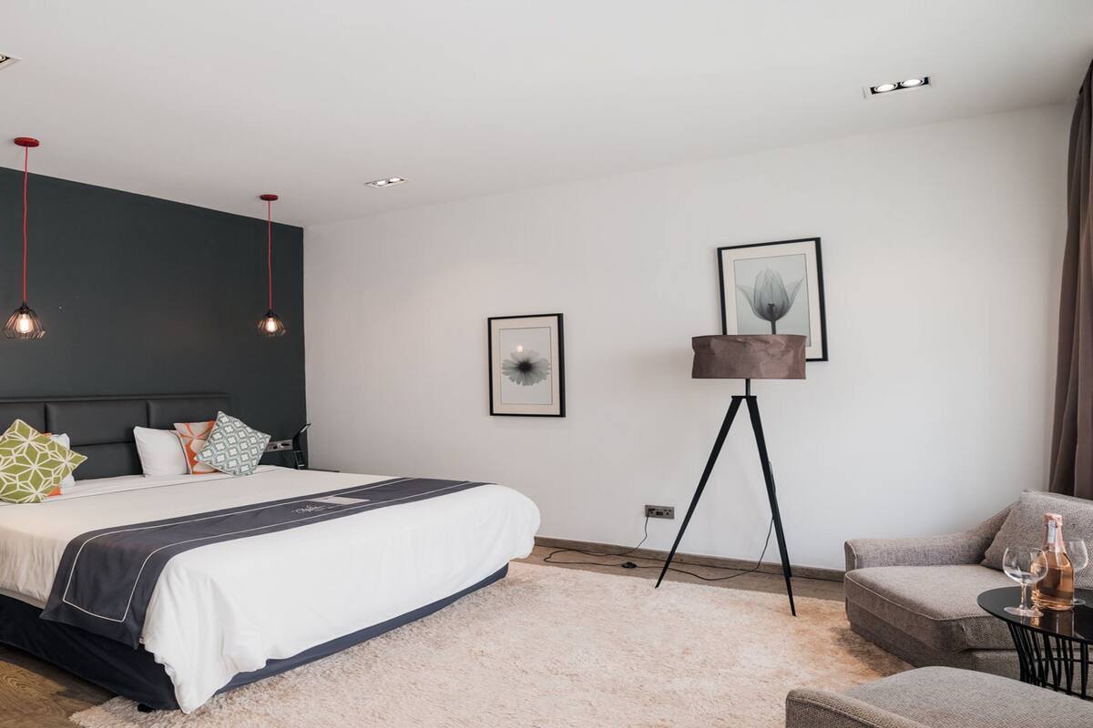 Un dormitorio moderno con una cama grande, una lámpara de pie y un sofá.