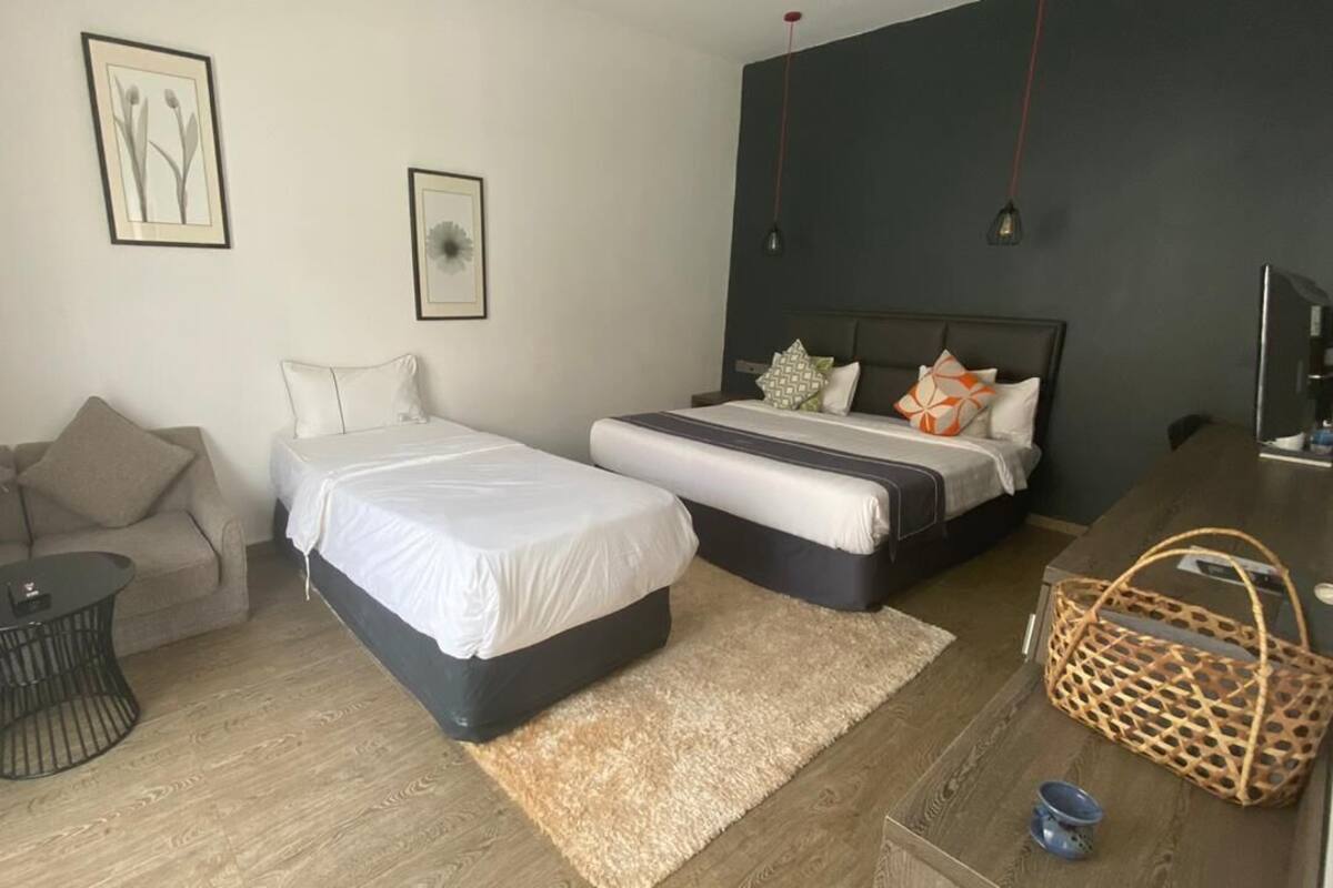 Una habitación de hotel con dos camas, un sofá, una mesita y un televisor.