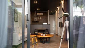 Una cocina moderna con encimera de madera, una zona de comedor con mesa redonda y taburetes, y un trípode en la esquina.
