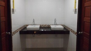 Un baño con dos lavamanos, una encimera negra y un salpicadero de azulejos.