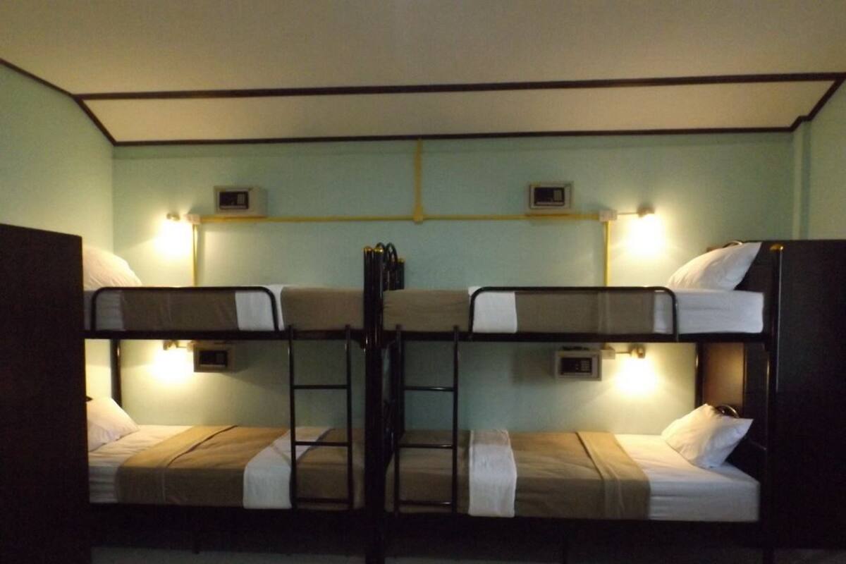 Ein Mehrbettzimmer mit zwei Betten, jeweils mit Nachttisch und Lampe.