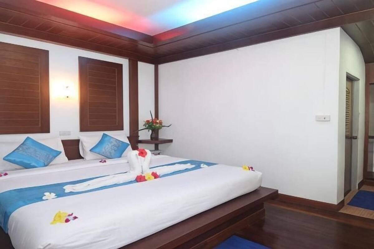 Ein Hotelzimmer mit einem großen Bett, einem Holzkopfstück, einem kleinen Tisch mit einer Vase und einer Treppe, die in einen anderen Raum führt.