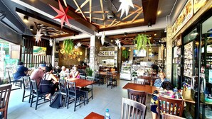 Een restaurant met houten tafels en stoelen, hangplanten en verschillende soorten eten die aan de muren worden gepresenteerd.