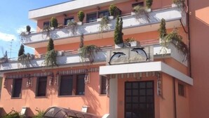 A building with multiple balconies, some with plants. The sign reads "Delfi". - Albergo Ristorante Delfino (Novara)