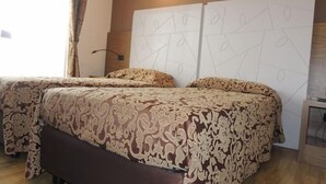 A double bed with patterned bedding, a bedside table, and a wall-mounted light fixture. - Albergo Ristorante Delfino (Novara)