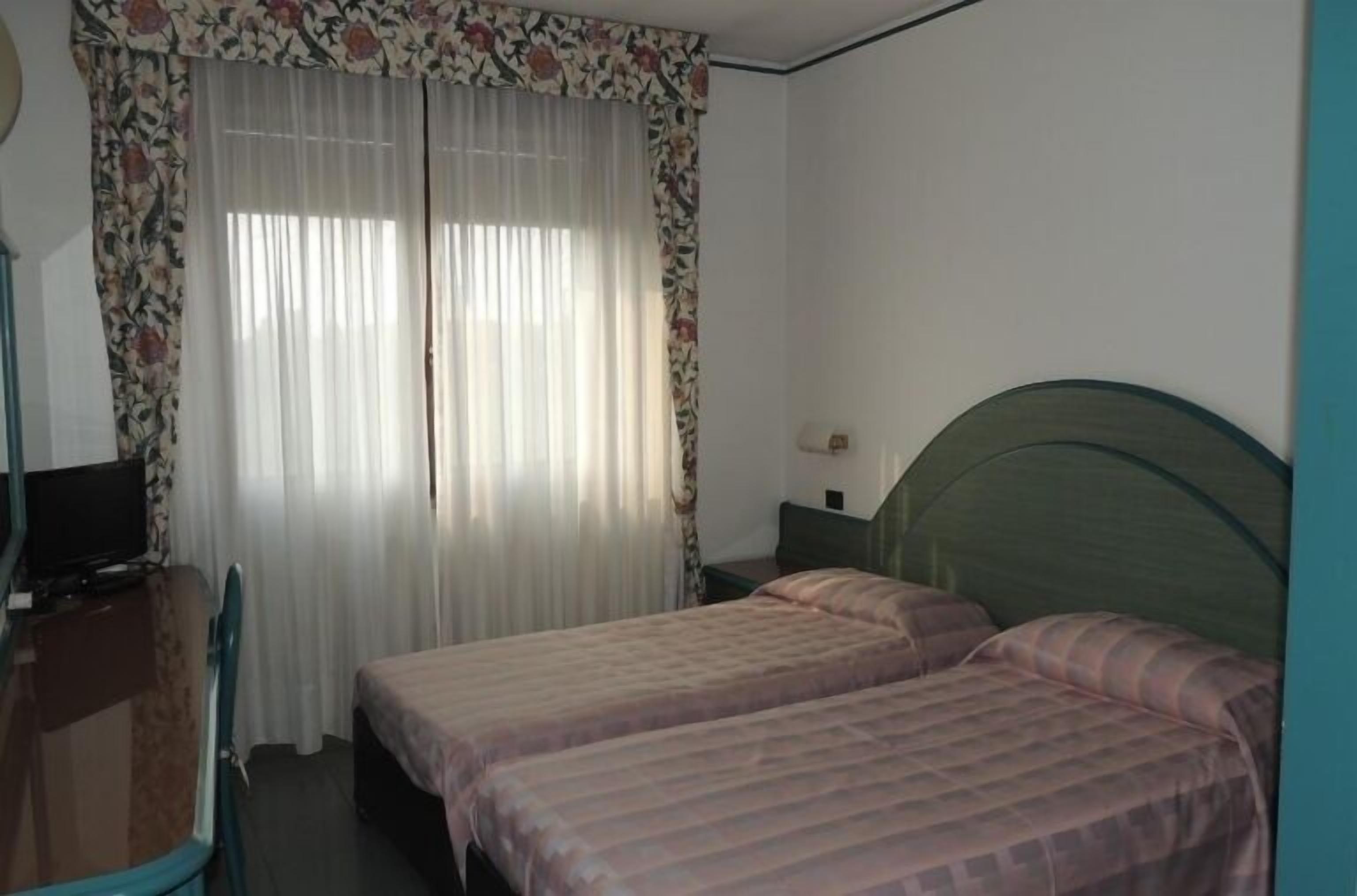 Ein Schlafzimmer mit zwei Betten, einem Schreibtisch und einem Fernseher.