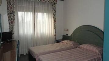 Ein Schlafzimmer mit zwei Betten, einem Schreibtisch und einem Fernseher.