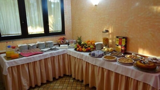 A buffet table with various food items and beverages, set against a wall with a window. - Albergo Ristorante Delfino (Novara)