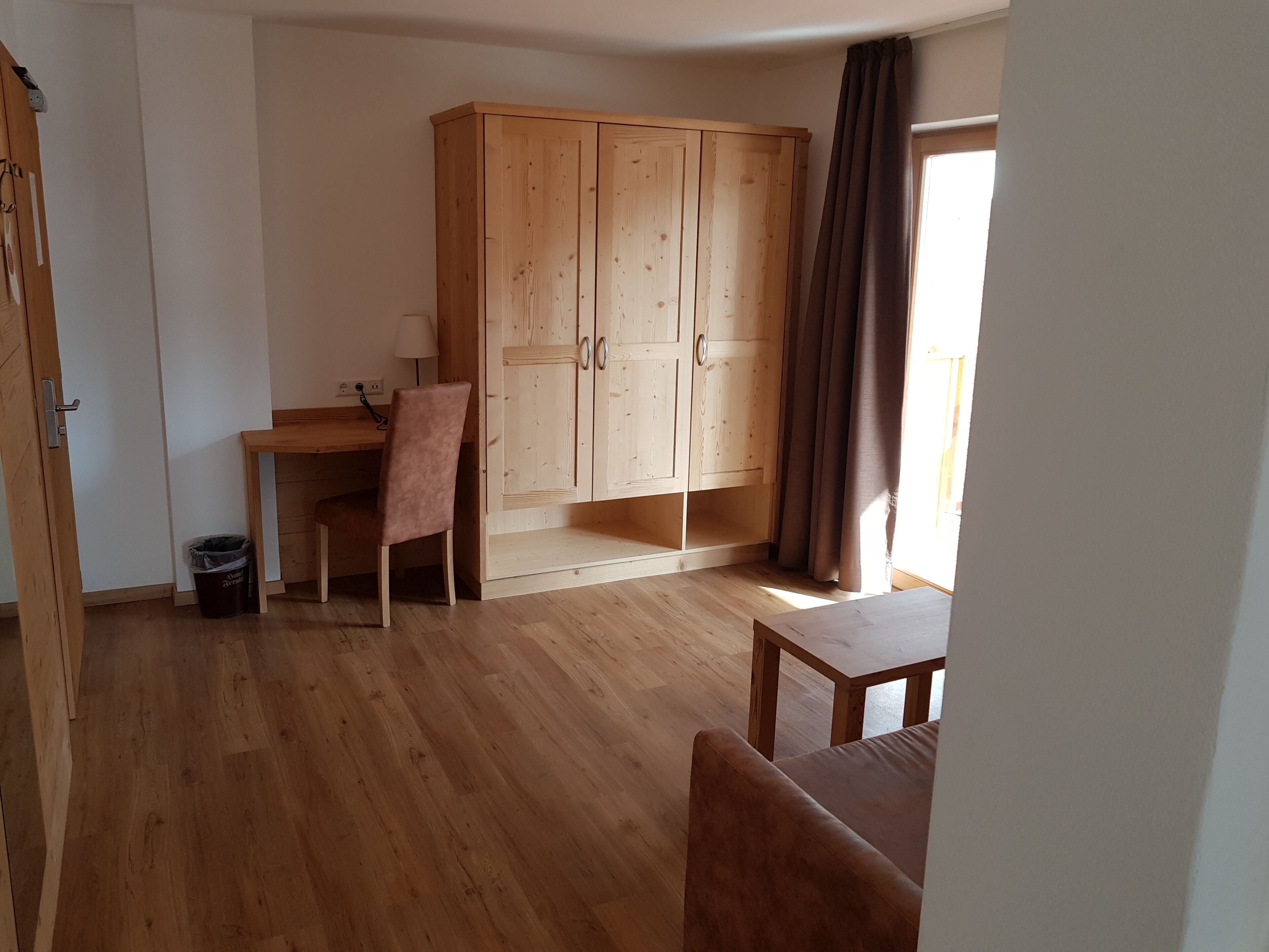 Une pièce comprenant un bureau en bois, une chaise, un placard et une petite table.