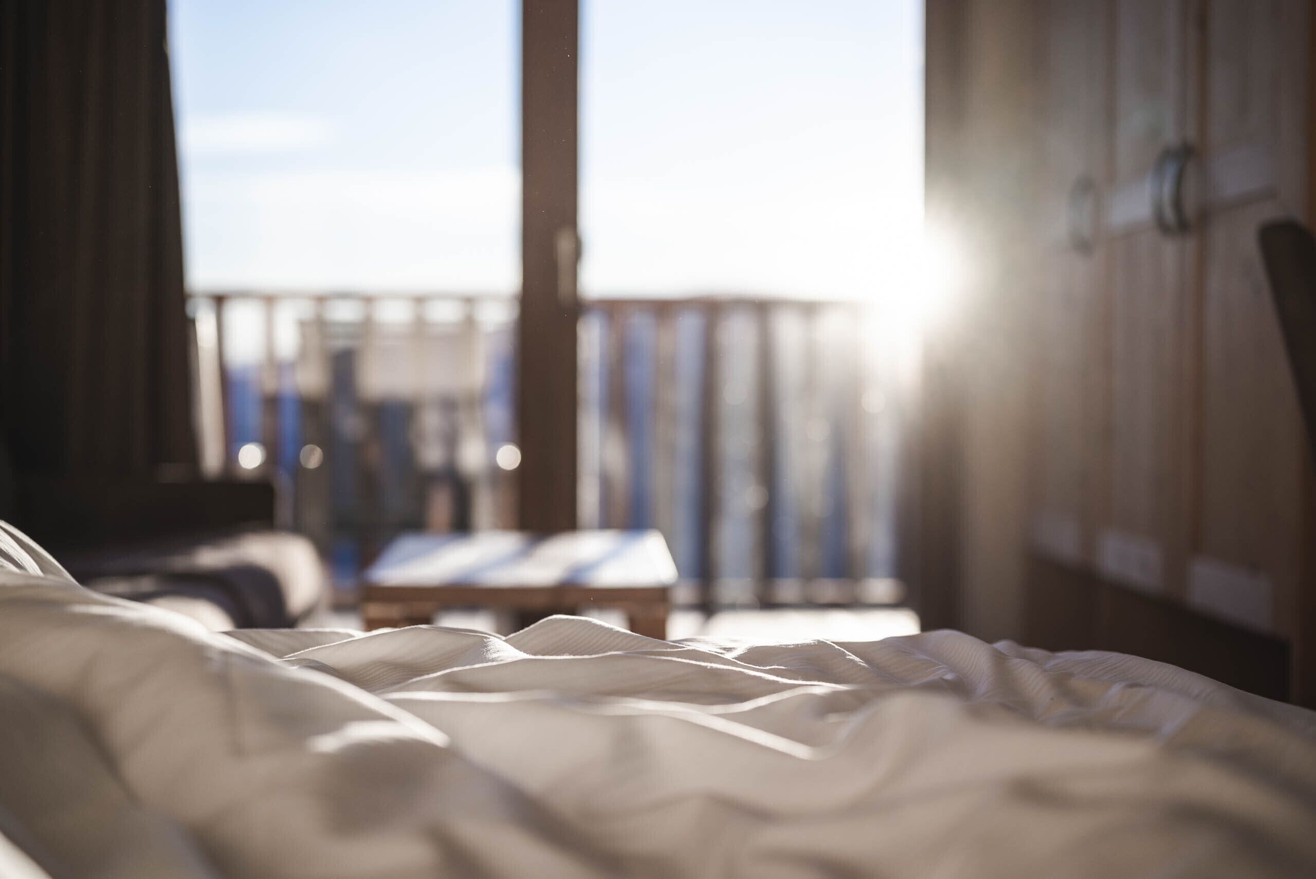 A bed with a view of a balcony and a wooden wall.