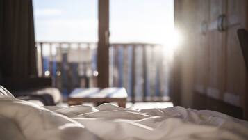 A bed with a view of a balcony and a wooden wall.