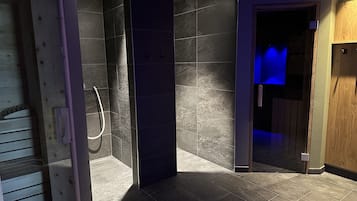 Bathroom features a shower area with a glass door and shower hose.