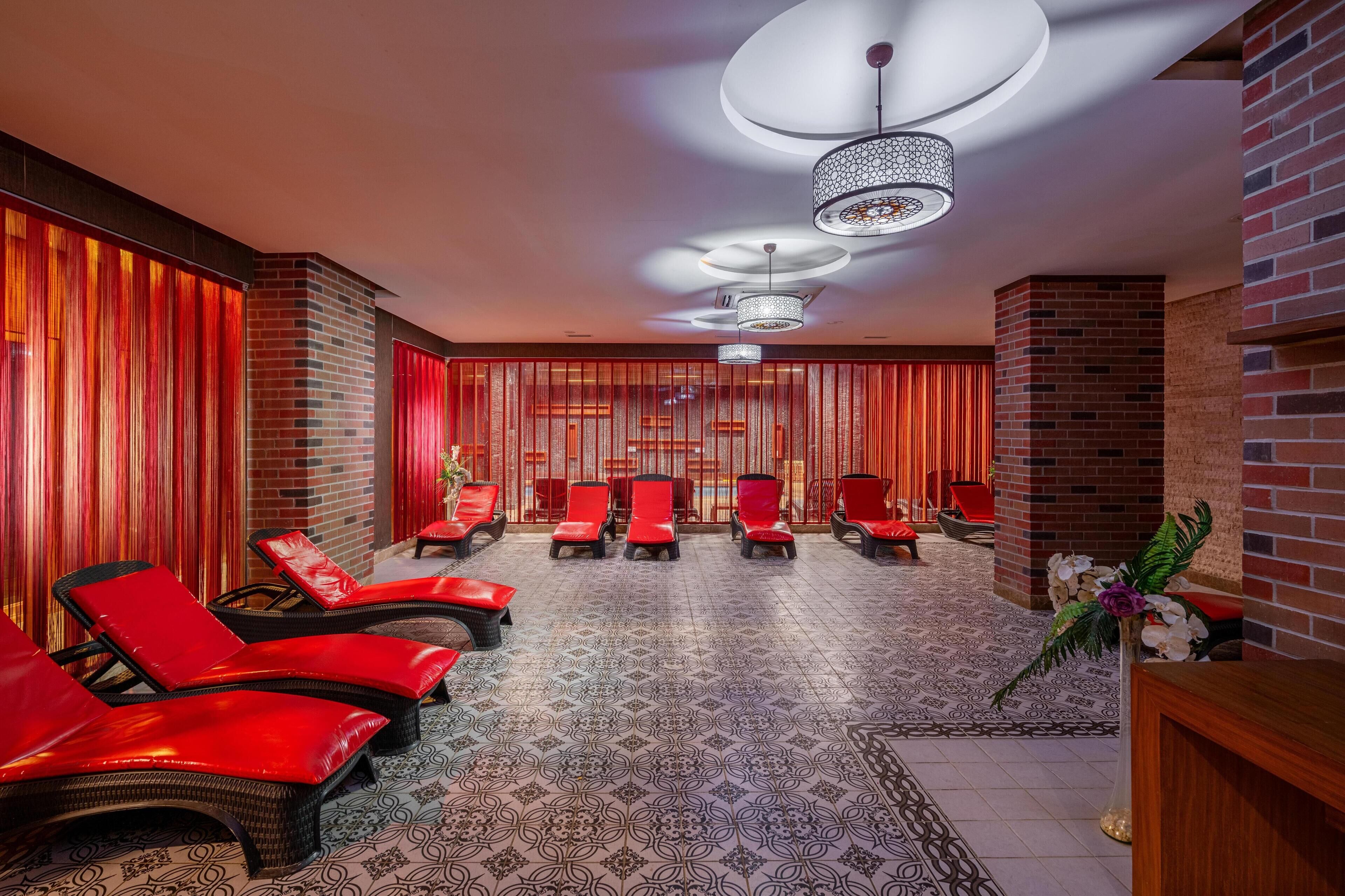 Un espace spa avec des fauteuils rouges, des carreaux de sol à motifs et un mur en briques.