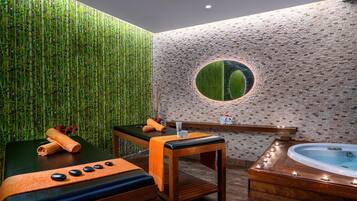 Een spa-ruimte met een massagetafel, een houten bankje, een jacuzzi en een muur met een ronde spiegel.