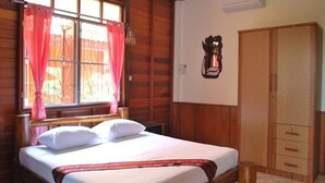A wooden-paneled room with a bed, a wardrobe, and a wall-mounted air conditioner. - 4T Guesthouse (Sukhothai)