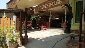 A guesthouse with a covered entrance, outdoor seating area, and potted plants. - 4T Guesthouse (Sukhothai)