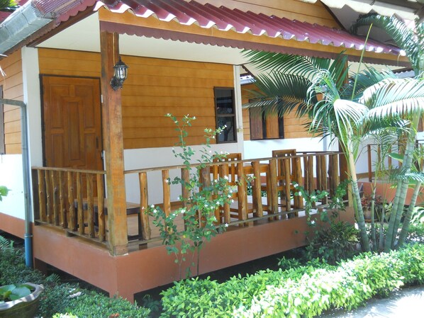 A wooden house with a porch, a door, and a window.